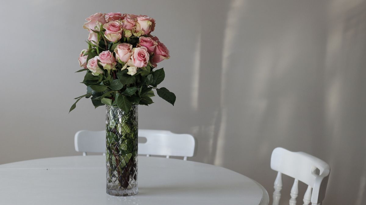 Rosen in Kristallvase auf weißem Tisch